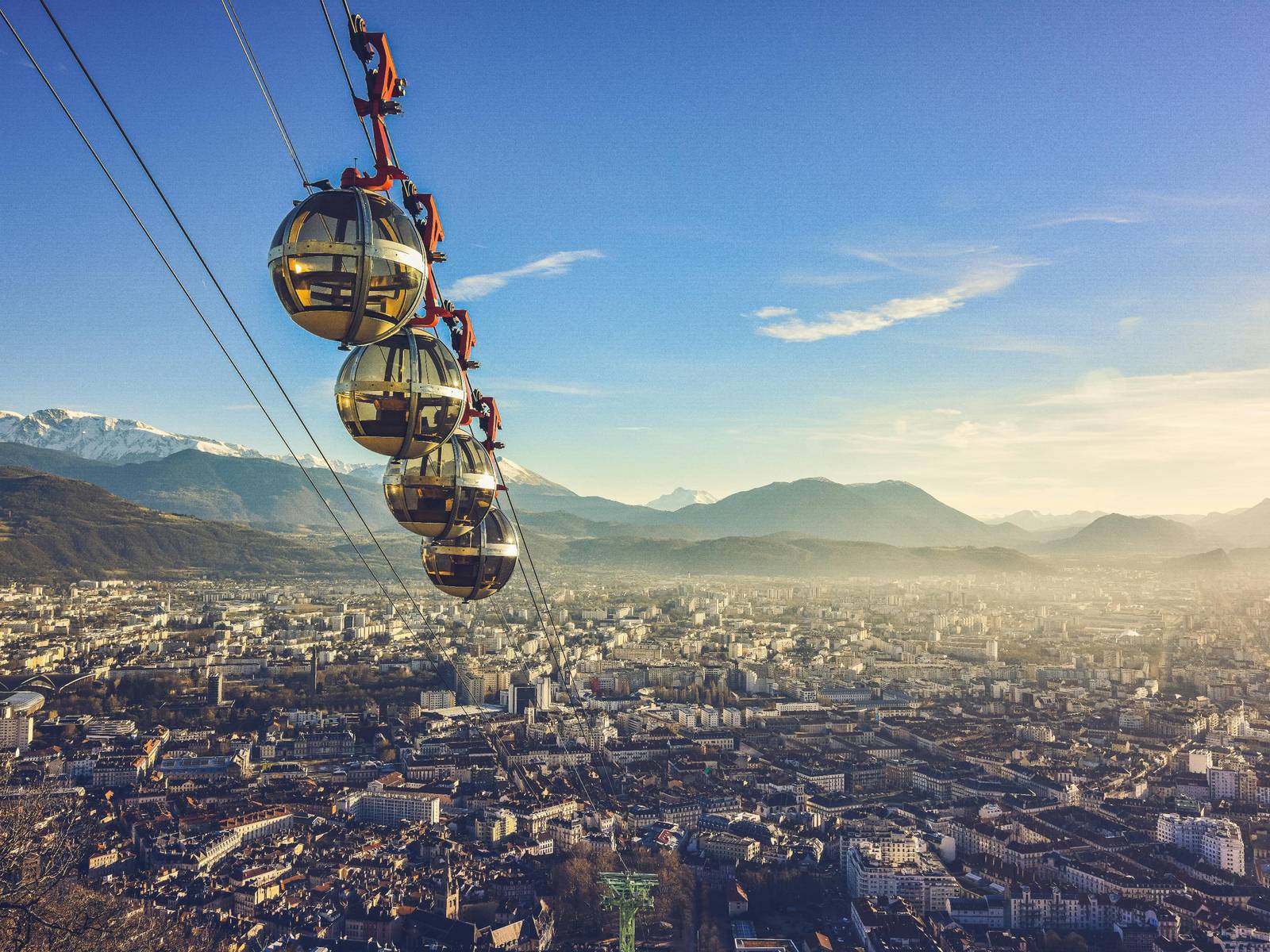 Les quatre bulles du téléphérique de la Bastille au-dessus des toits de Grenoble, face aux montagnes enneigées